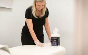 Massage therapist disinfecting a massage table with Prevention Disinfectant Wipes