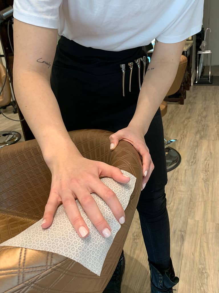 Hair stylist wiping down chair using Prevention Wipe