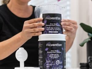 Beauty professional refilling a Prevention Disinfectant Wipes canister with a refill pouch