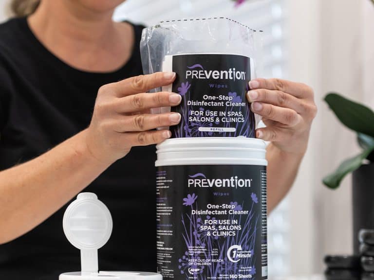 Beauty professional refilling a Prevention Disinfectant Wipes canister with a refill pouch