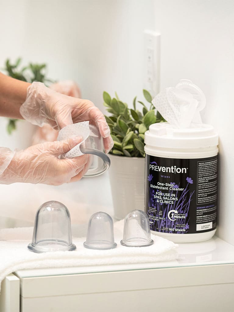 Massage therapist disinfecting massage cups with Prevention Wipes