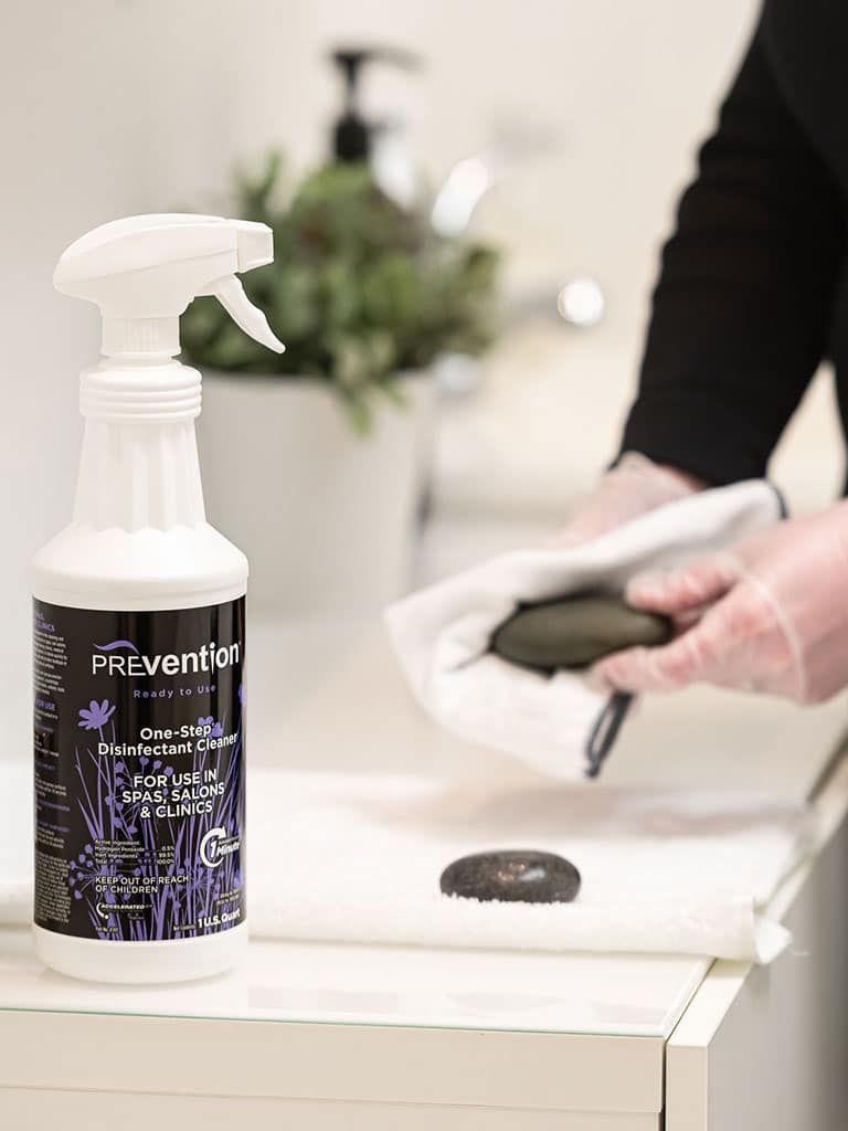 Massage therapist disinfecting massage stone with Prevention Wipes